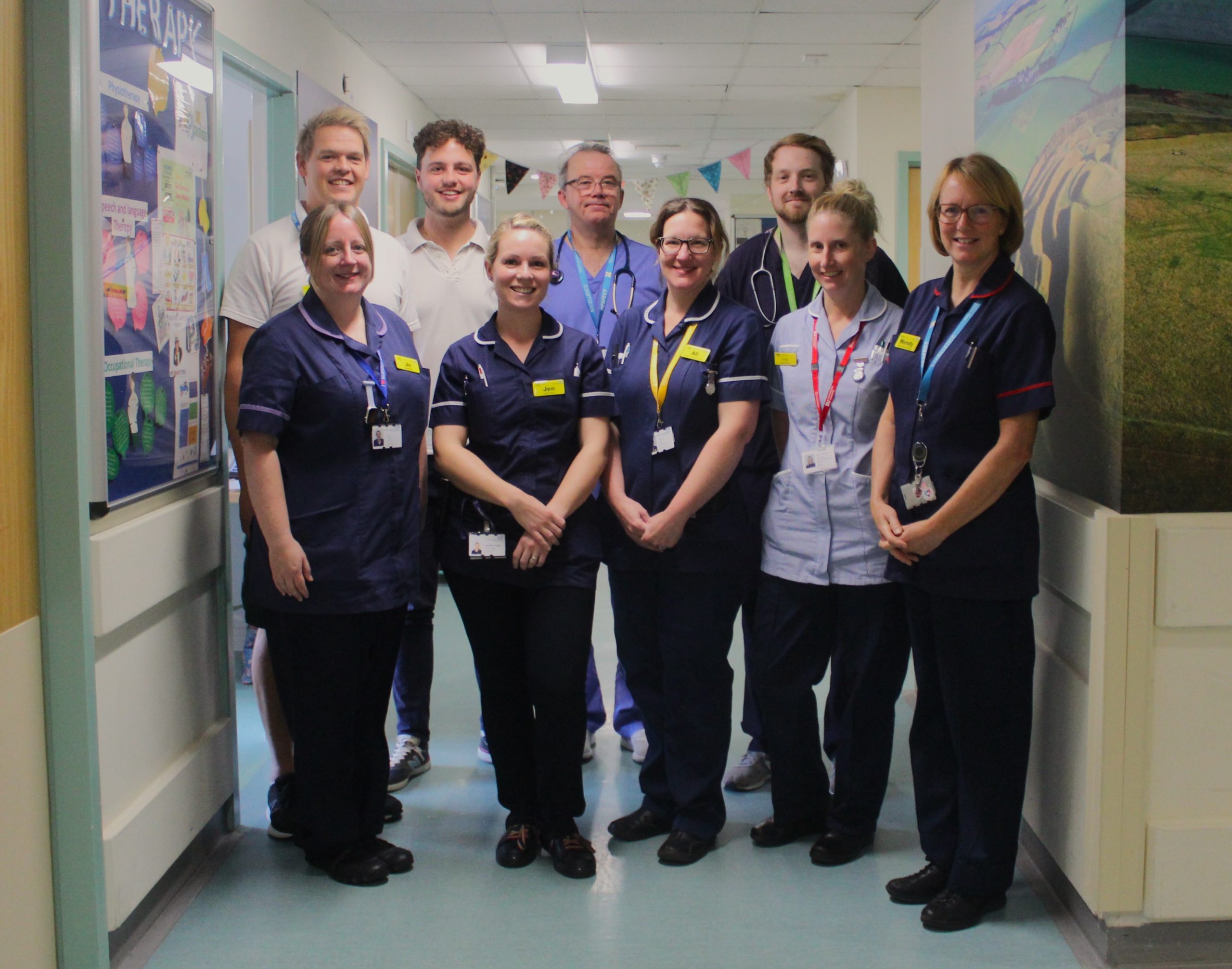 A number of healthcare workers standing together in a hospital ward.