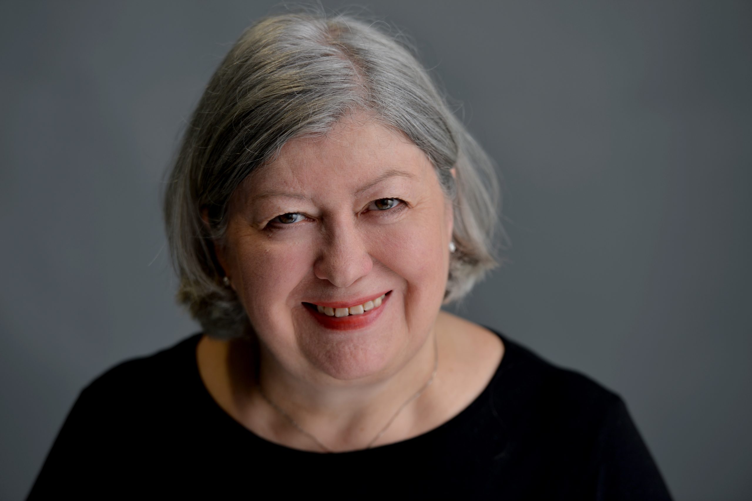 A person smiling at the camera. She is wearing a black t-shirt.
