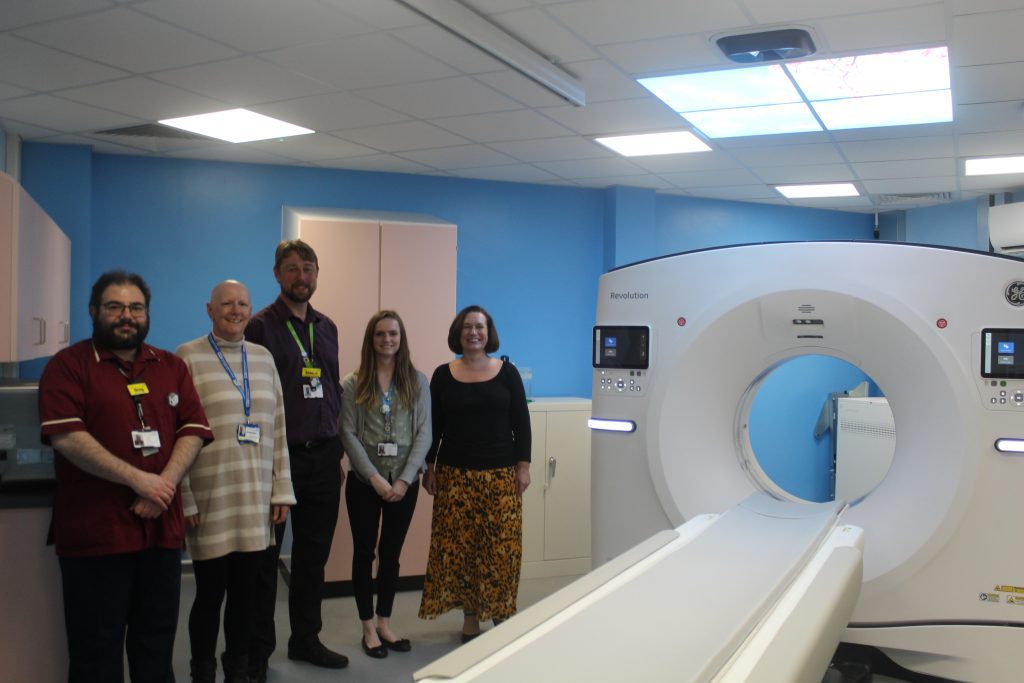 Staff by the new beside the new CT Scanner at Weymouth Community Hospital.