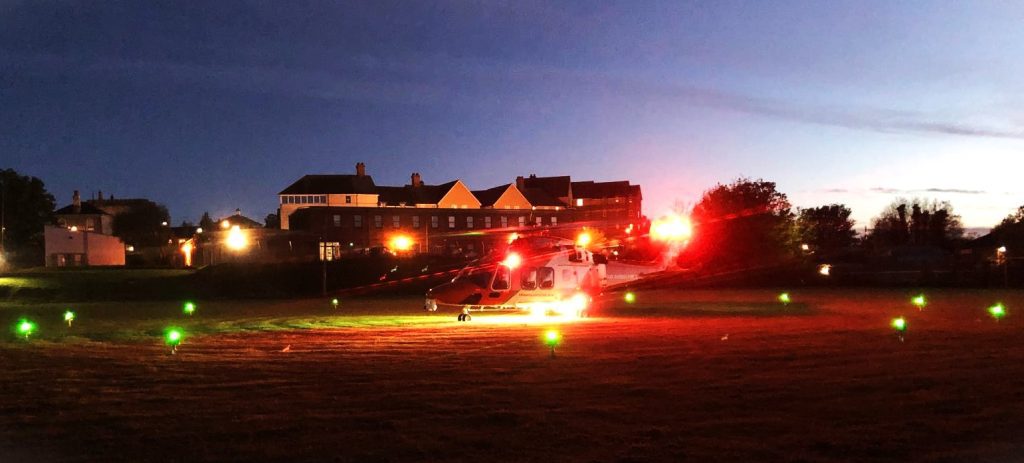 Helicopter at night on field surrounded by lights