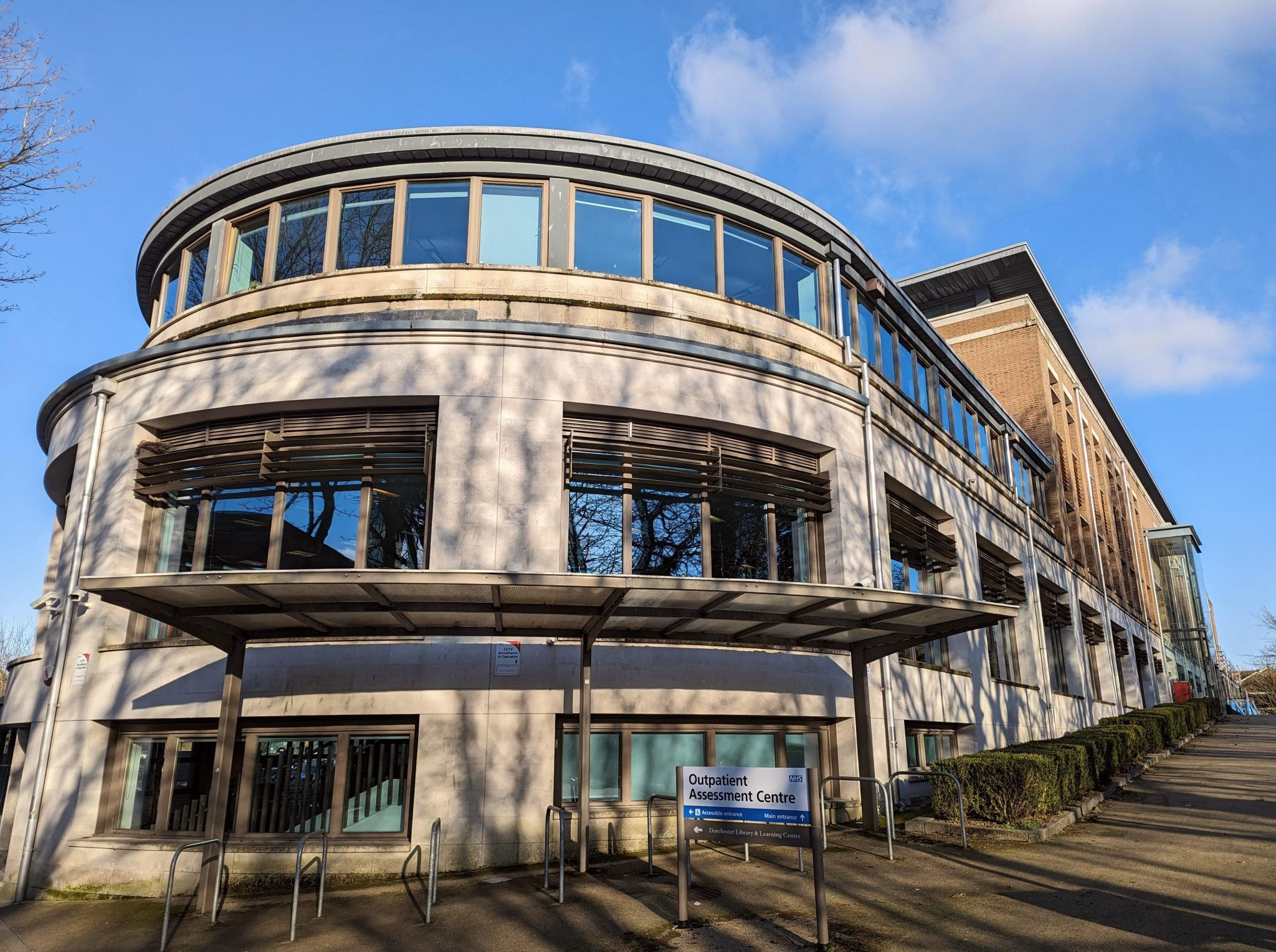 An exterior image of a building. A sign in the foreground reads 'Outpatient Assessment Centre'.