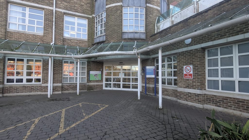 A white entrance with signs for South Wing 1