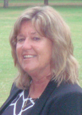 A woman in a blouse and jacket, smiling at the camera.