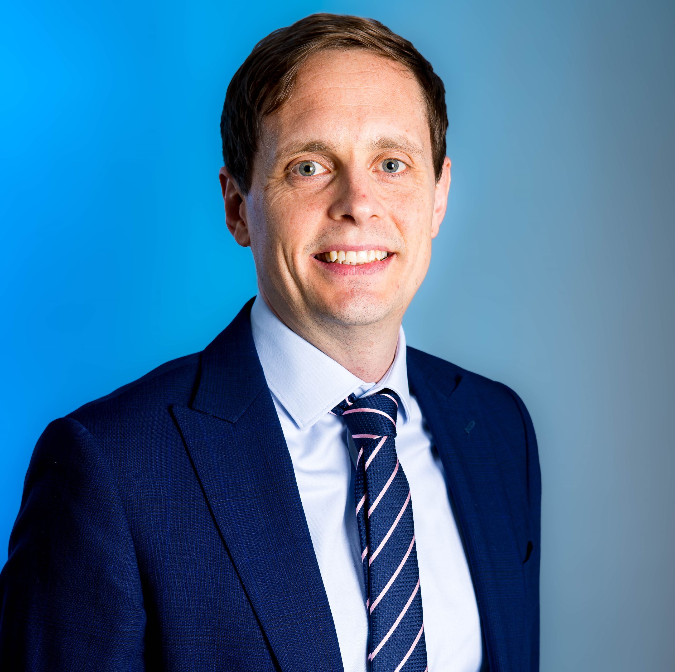 A person in a shirt and tie smiling at the camera.