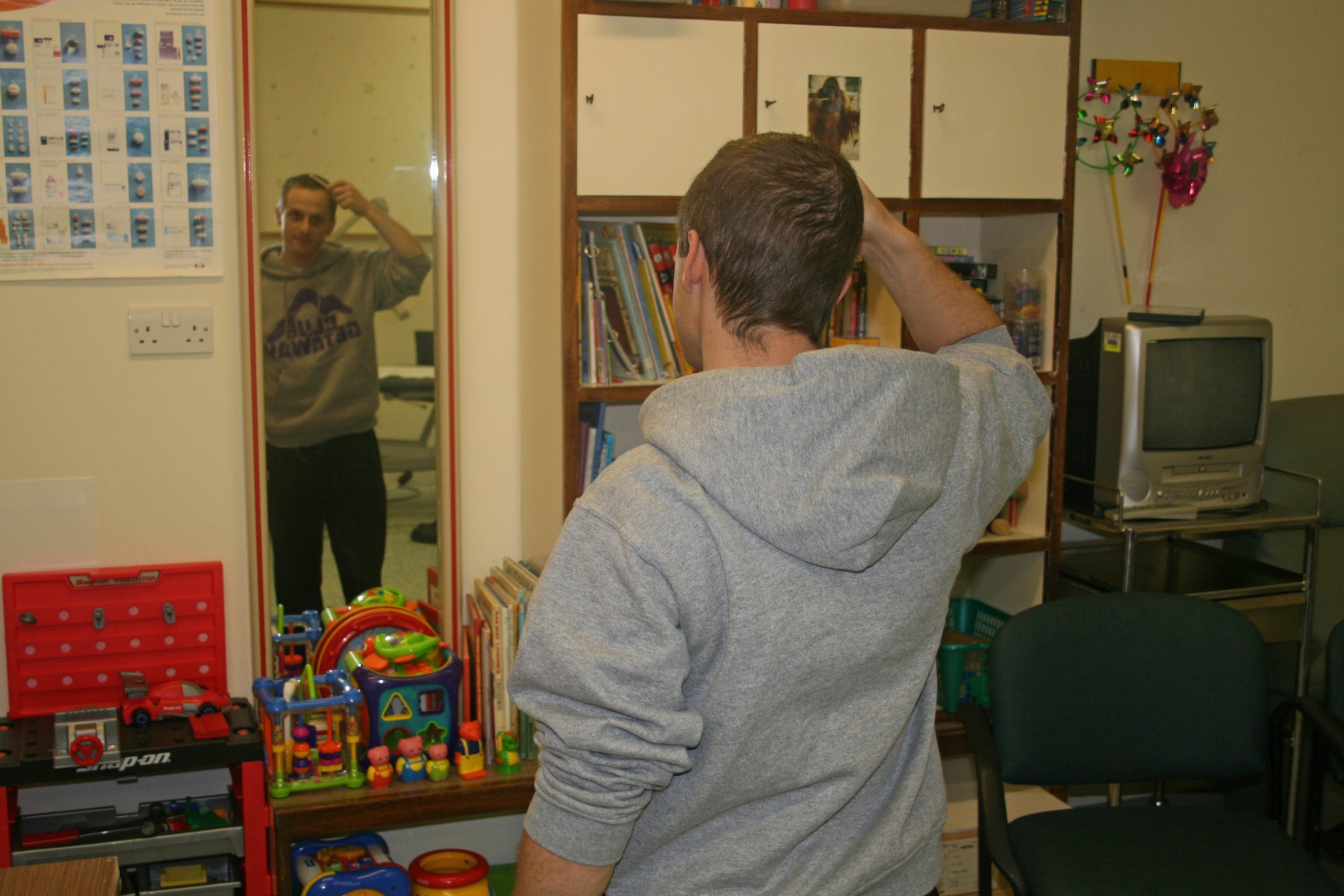 A person standing in front of a mirror, combing his hair.