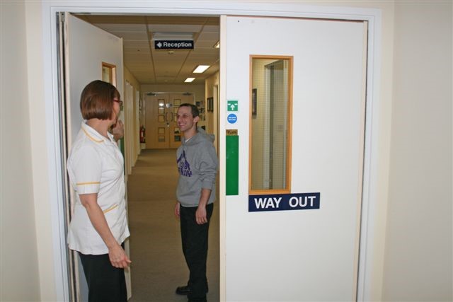 A healthcare worker welcoming a patient into a hospital department.