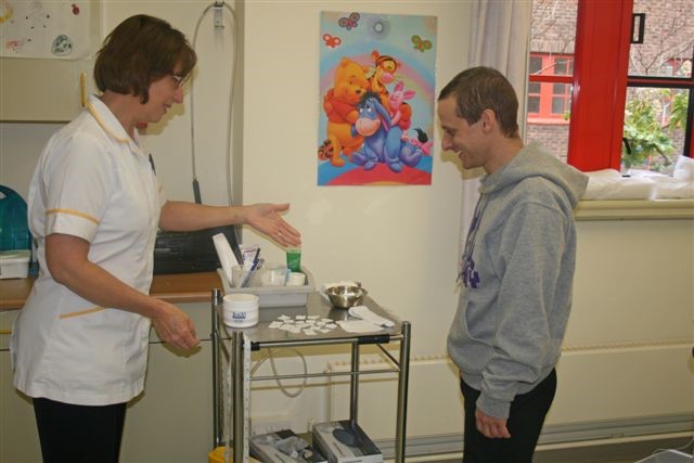 A healthcare worker showing a patient a trolley which contains a number of items.