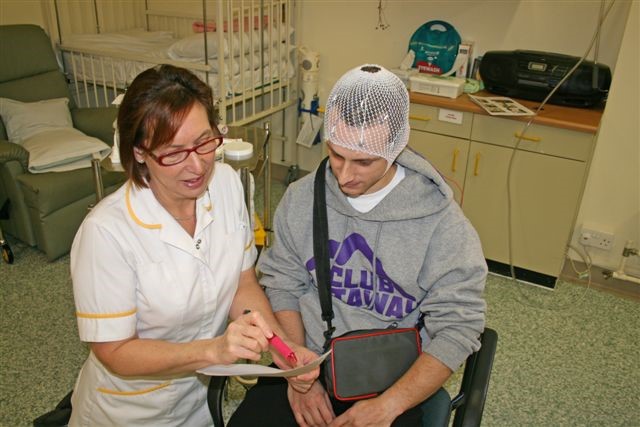 A healthcare worker is talking a patient through a form. She is holding a pink pen.