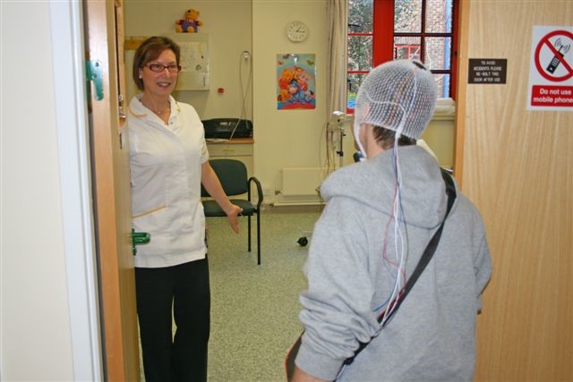 A healthcare worker welcomes a patient into a side room of a department.