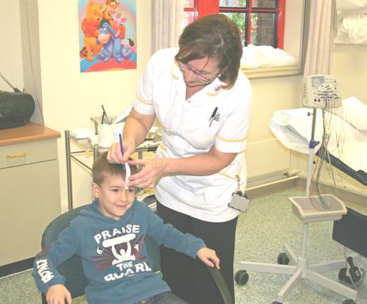 A healthcare worker is measuring a young child's head with a measuring tape.