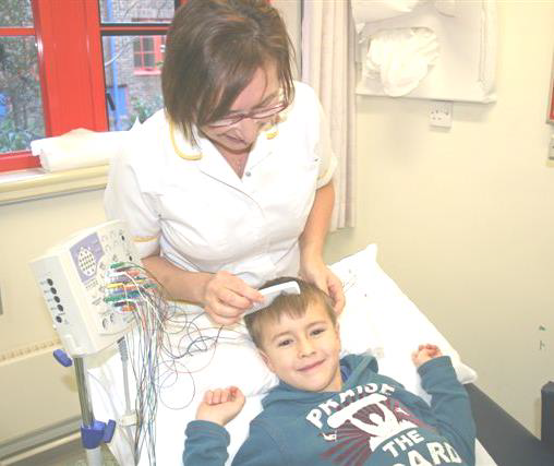 A healthcare worker is brushing a young child's hair.