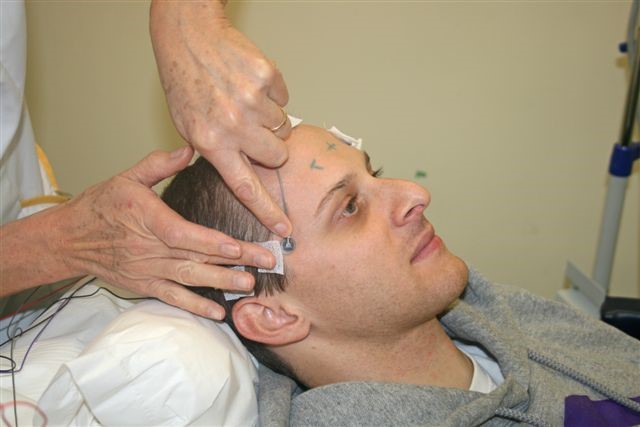 A healthcare worker placing wires on a patient's head.