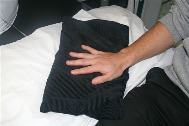 A person's hand places on a black warming blanket.