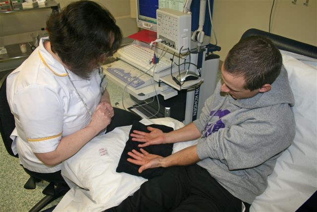 A healthcare worker examining a person's hands in a clinical setting.