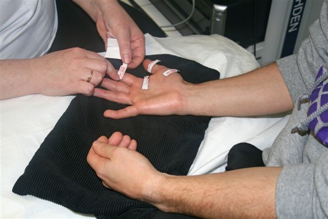 A person removing stickers and wires from another person's hand.