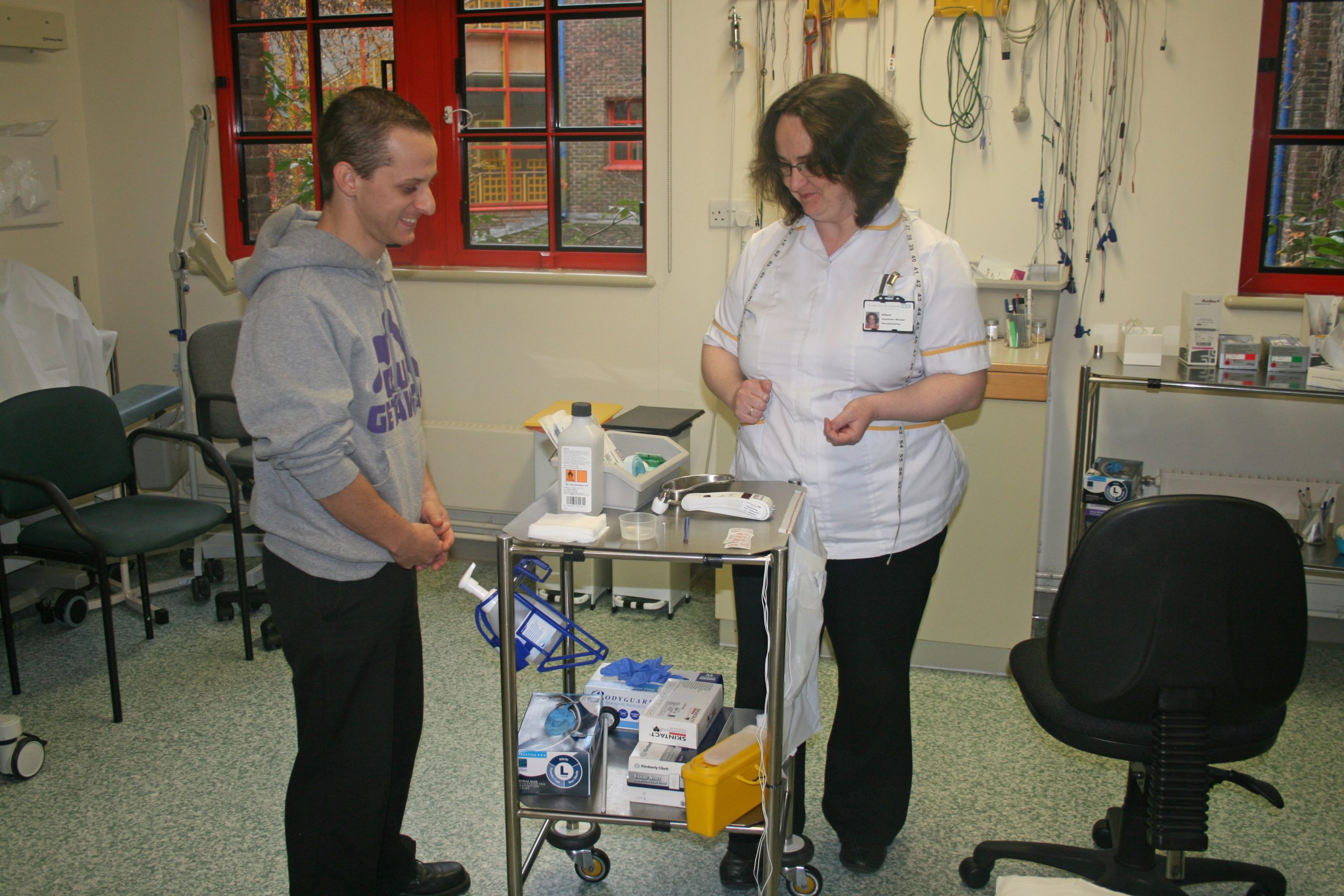 A healthcare worker showing a patient a trolley which contains a number of items.