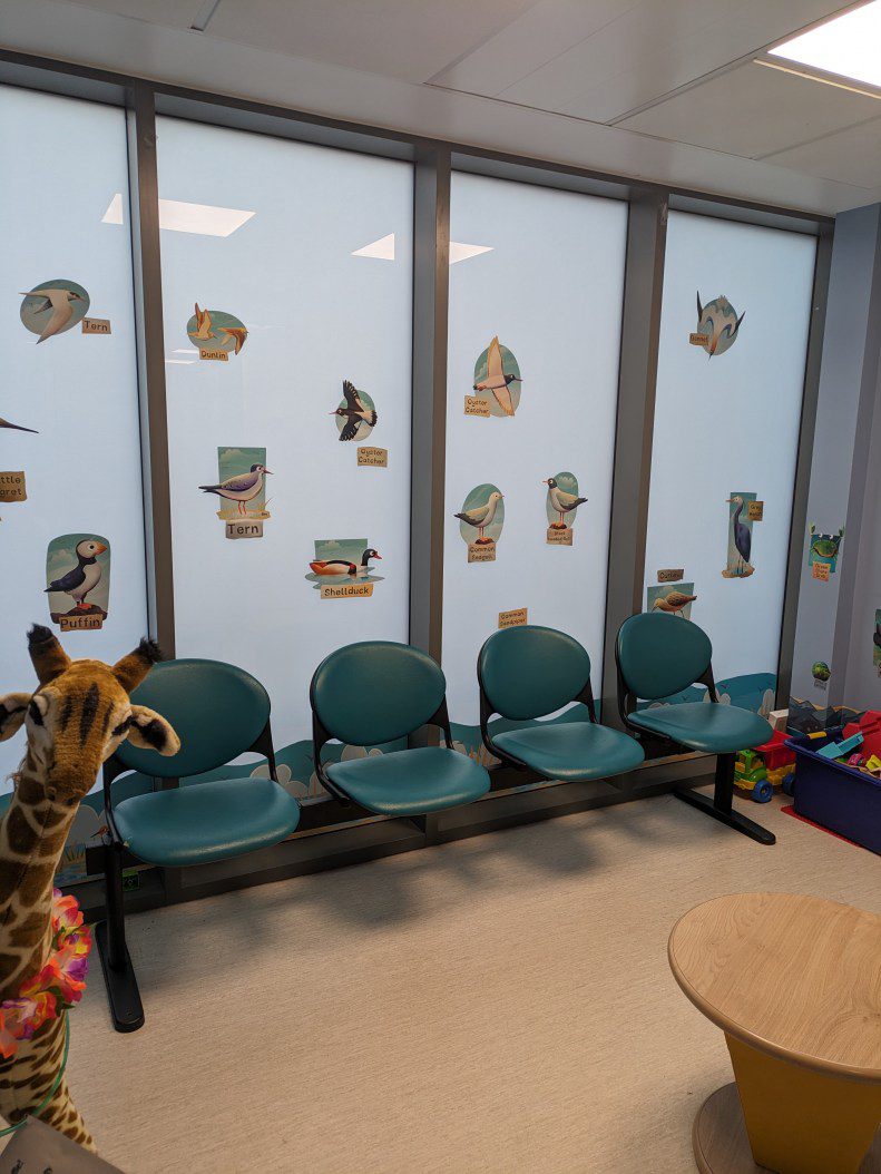 A brightly lit room with seats, a table and toys.
