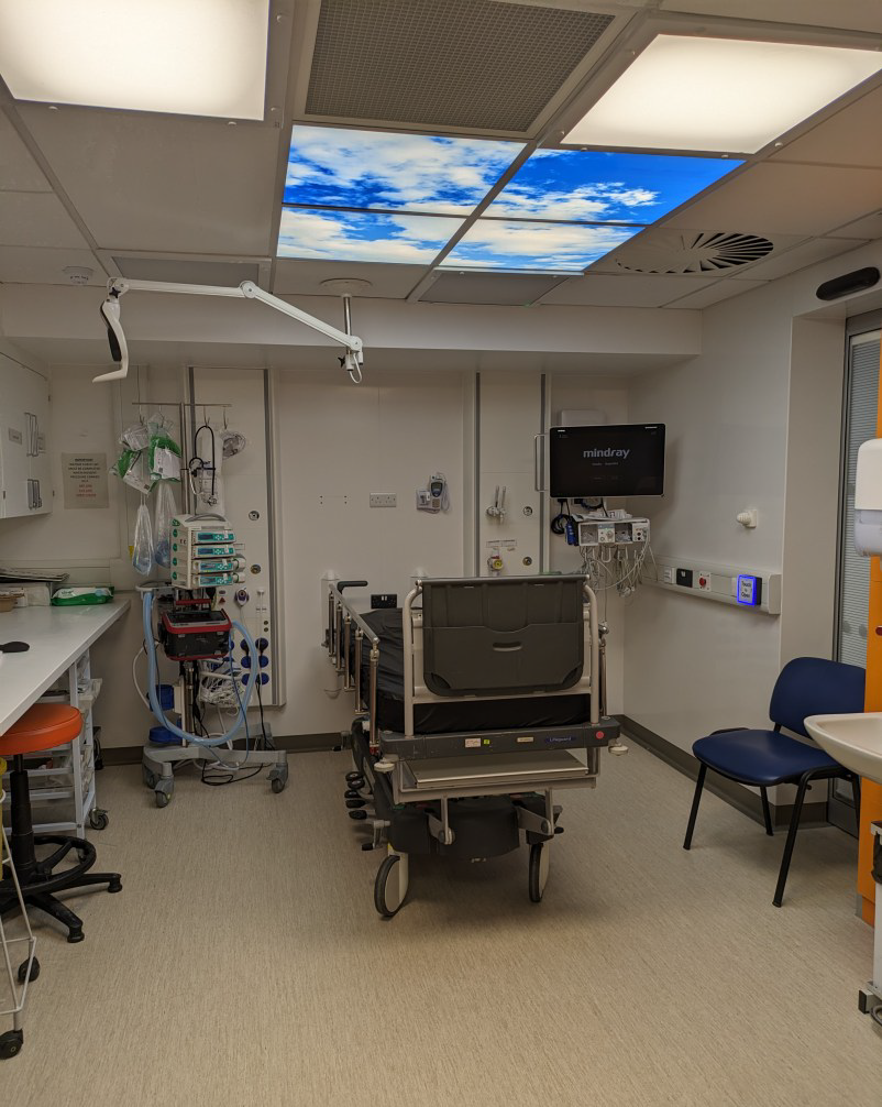A brightly lit room in a hospital. There is medical equipment in the room, as well as a bed.