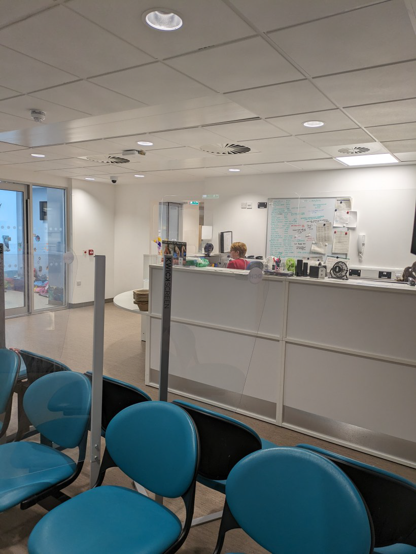 A receptionist sitting behind a desk in a waiting room.