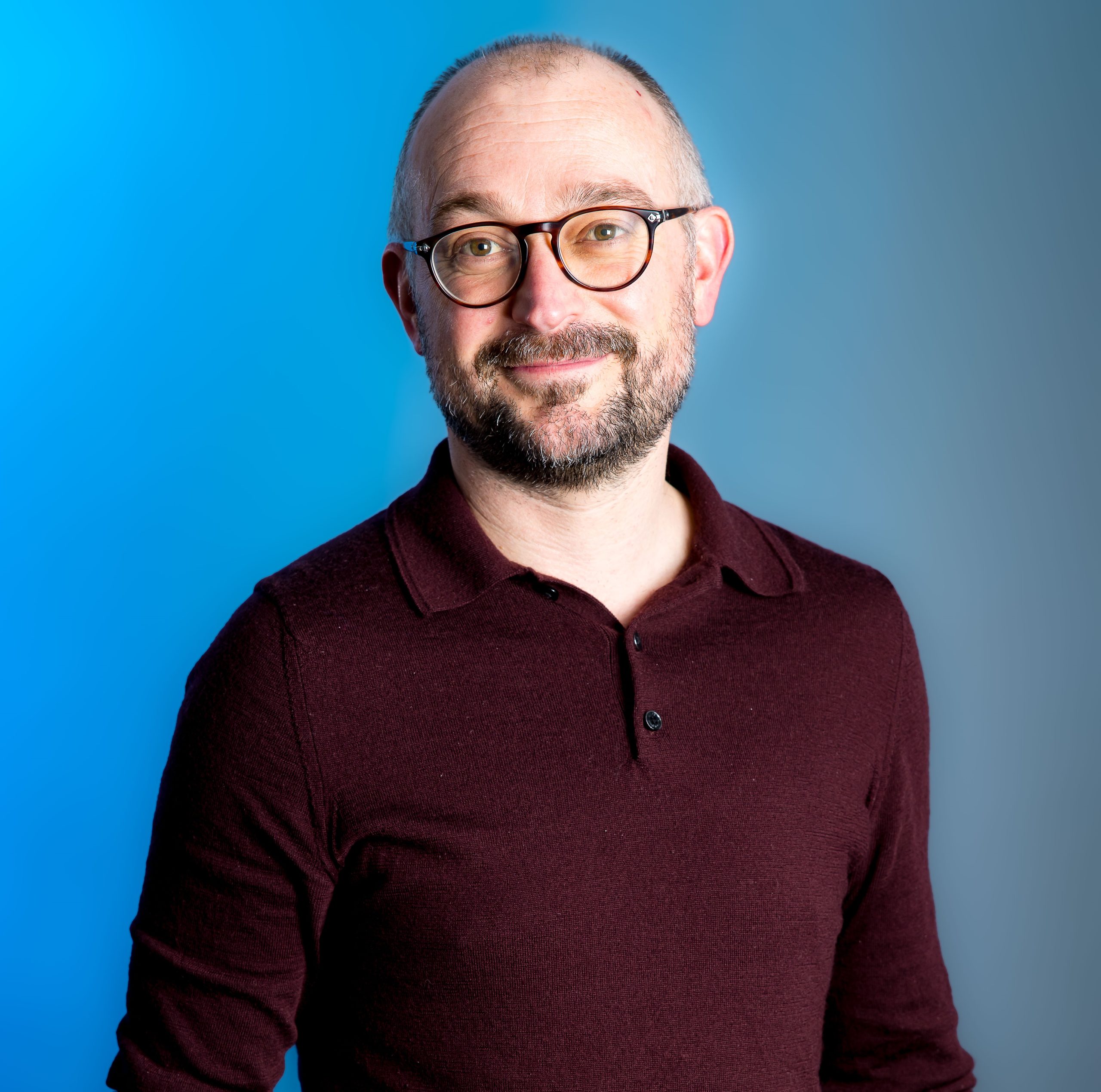 A person in glasses smiling at the camera.
