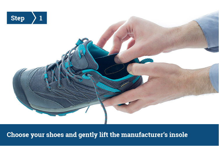 Hands placing an insole into a blue and grey trainer.