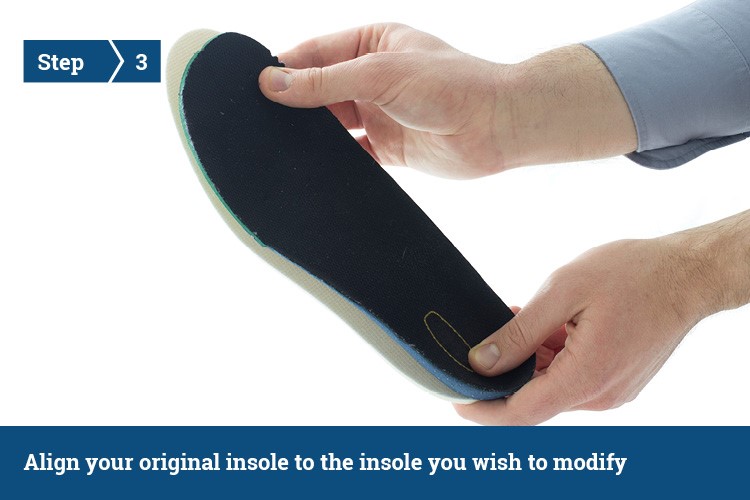 A person holding two insoles, measuring them against each other.