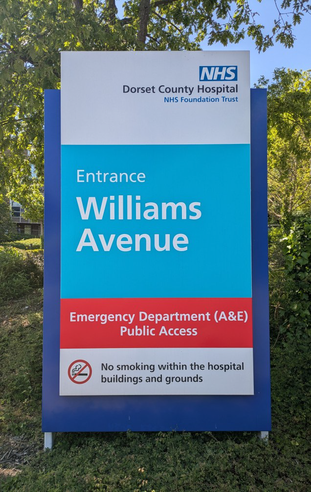 An outdoor sign that reads 'Entrance, Williams Avenue, Emergency Department (A&E), Public Access, No smoking within the hospital buildings and grounds. There is a NHS logo in the top right.