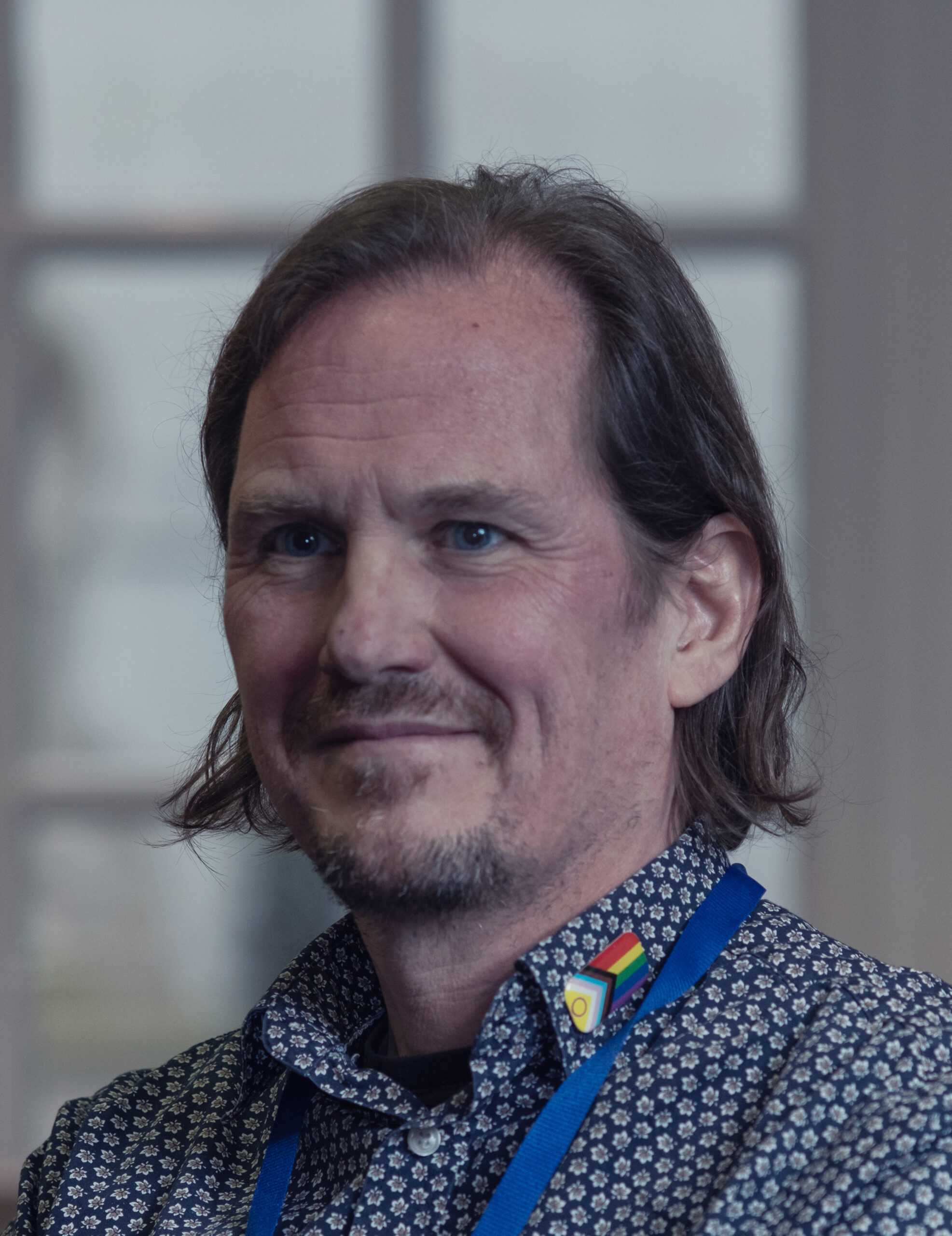 A person in a shirt and lanyard smiling at the camera.