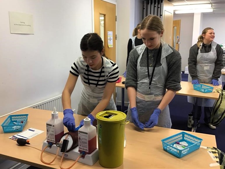 Two students practicing a task with medical equipment.