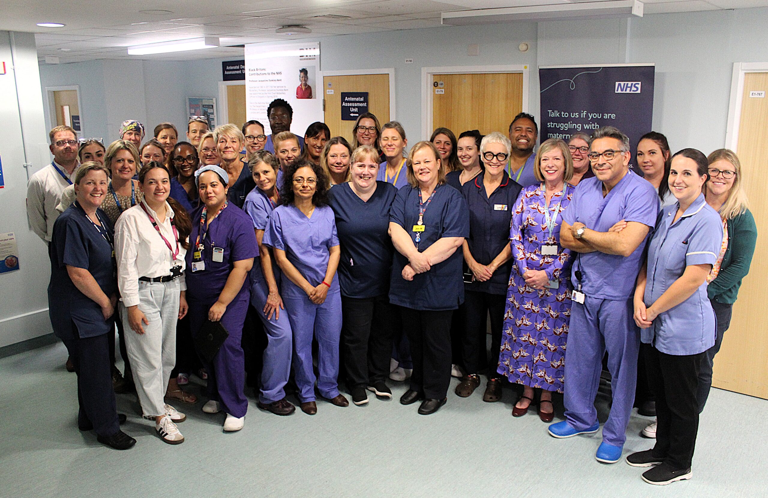 A large group of healthcare professionals standing in a ward. They are all smiling at the camera.