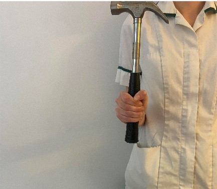 A healthcare professional holding a hammer with one hand.