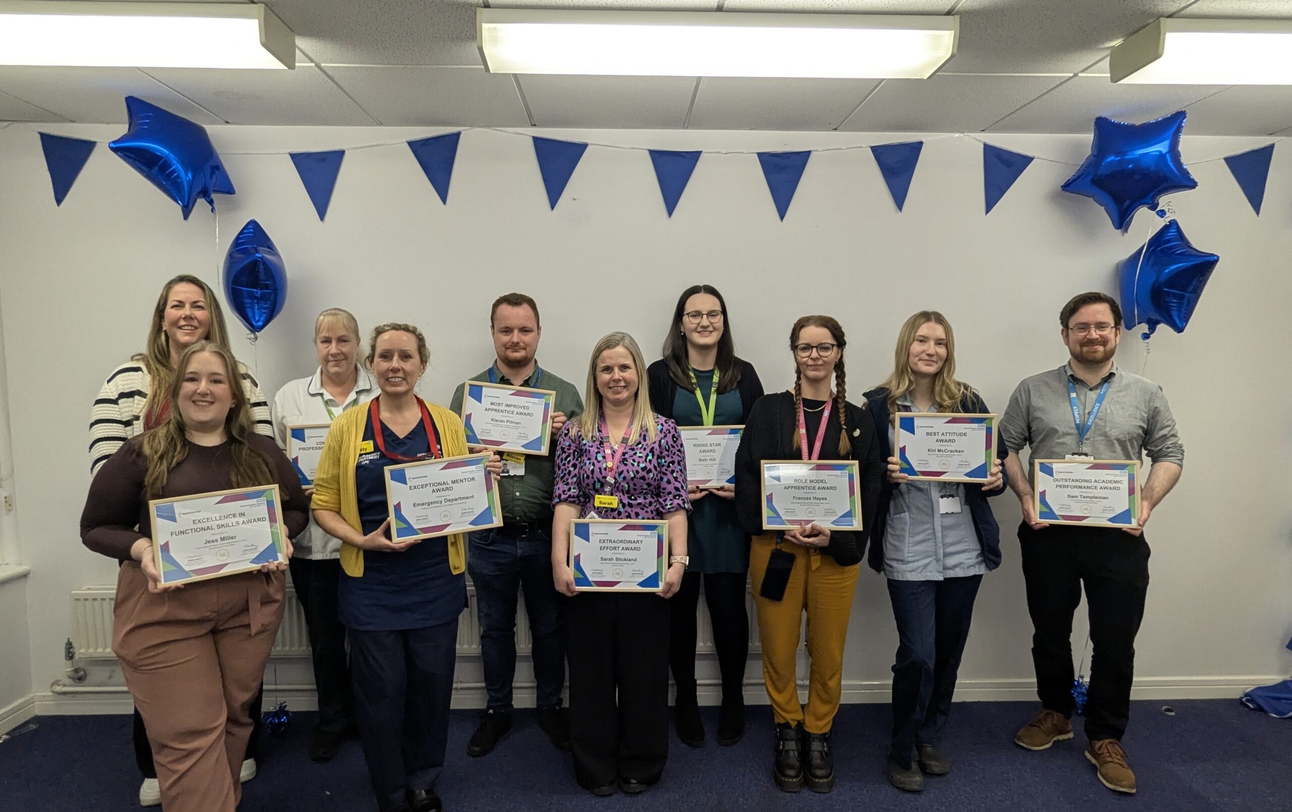 A group of people with certificates in front of balloons