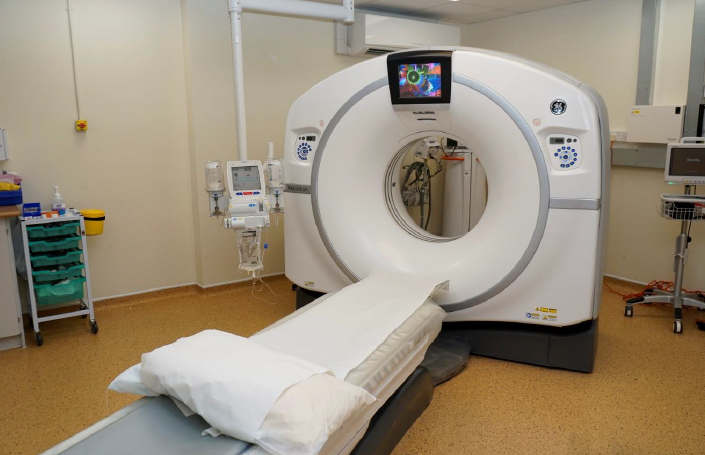 A CT scanner in a hospital room. There scanner is surrounded by various hospital equipment.