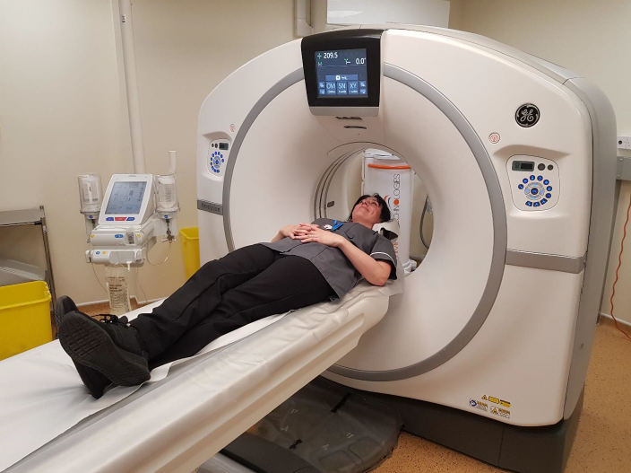 A CT scanner in a hospital. A person is lying on the scanner, demonstrating how the scanner works.