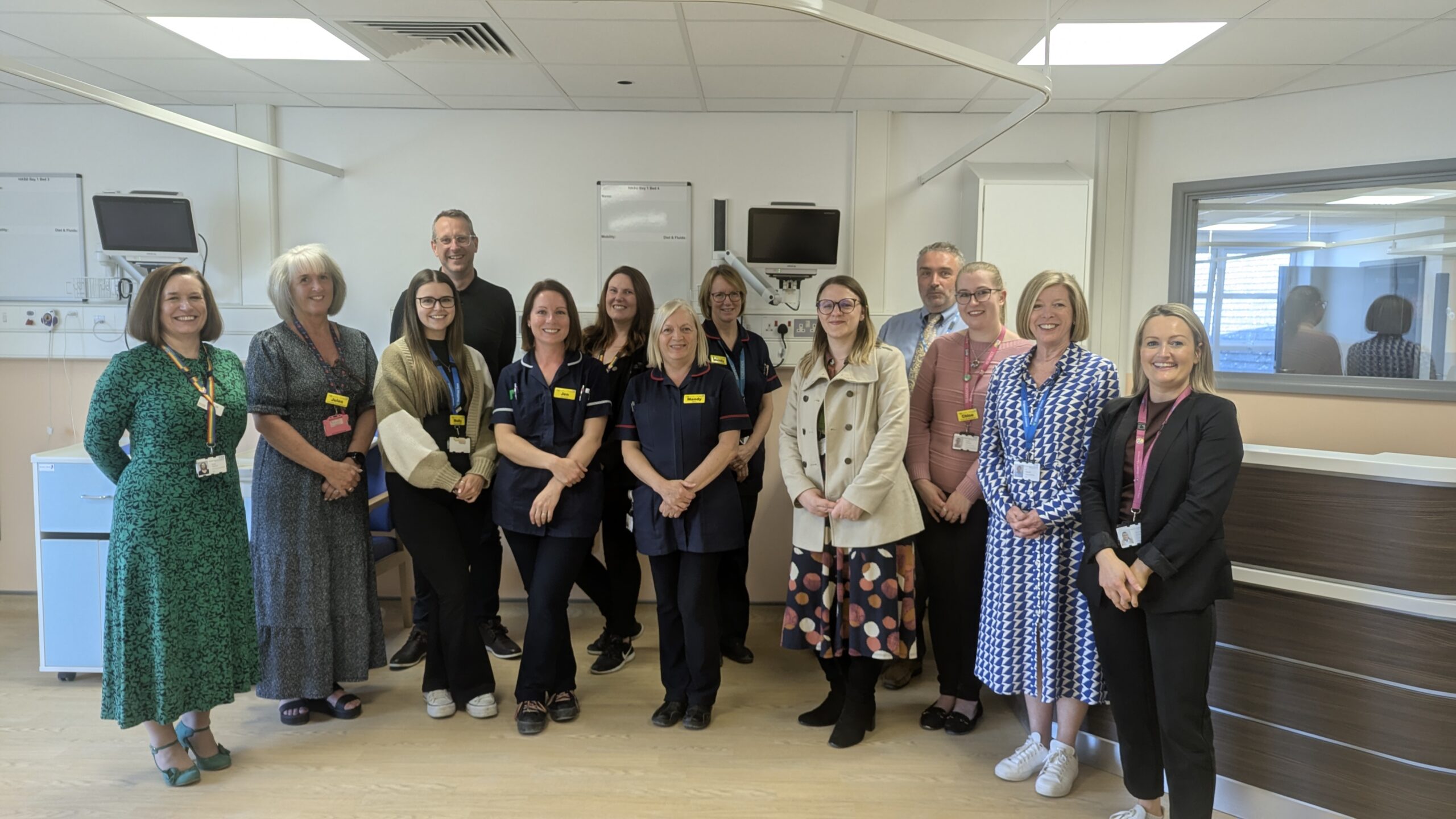 A group of people stood in a new hospital ward by a desk
